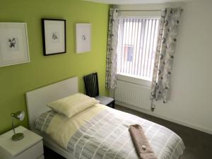 ein grünes Schlafzimmer mit einem Bett und einem Fenster in der Unterkunft 17 Aspen Road in Rugby