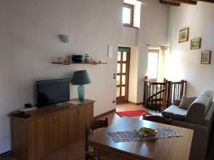 ein Wohnzimmer mit einem Sofa, einem TV und einem Tisch in der Unterkunft Casa Nadia in San Zeno di Montagna