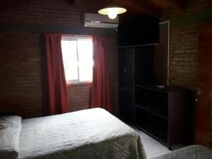 1 dormitorio con 1 cama y una ventana con cortinas rojas en Ariel Reynoso - Departamento Planta Alta en Mina Clavero
