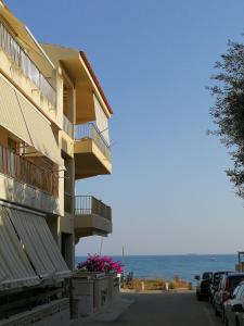 a building with balconies and cars parked next to the ocean at Colori a mare in Villaggio Azzurro