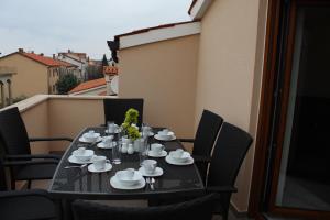 une table noire avec des tasses et des soucoupes sur un balcon dans l'établissement Casa Rados Fazana, à Fažana