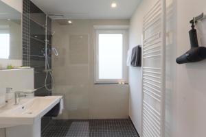 ein weißes Bad mit einem Waschbecken und einer Dusche in der Unterkunft Ferienwohnung Welcome mit Seeblick in Schalkenmehren