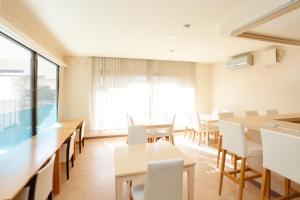 una sala da pranzo con tavoli e sedie bianche di Guest House Sonomama a Kōfu