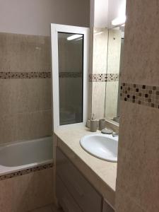 ein Badezimmer mit einem Waschbecken, einer Badewanne und einem Spiegel in der Unterkunft La Source in Le Gosier