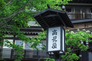 a street light with a sign in front of a building at Takamiya Ryokan Miyamaso in Zao Onsen