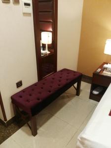 un banco rojo sentado en una habitación con una mesa en Al Aseel Hawazen Hotel, en La Meca