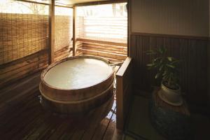 una grande vasca in legno in una stanza con una pianta di Takamiya Ryokan Miyamaso a Zaō Onsen