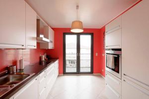 a kitchen with red walls and white cabinets at Rooftop Luxembourg Ville in Luxembourg