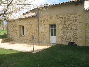 - un bâtiment en pierre avec une porte blanche dans une cour dans l'établissement Les Gites Du Chardon, à Teuillac