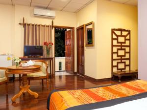 a room with a bed and a table and a desk at Chandara Boutique Hotel in Vientiane