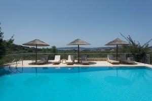 a swimming pool with chairs and umbrellas at Panorama Gialovas in Gialova