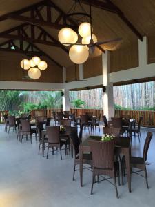 a dining room with tables and chairs and large windows at Casitas de Victoria in Nasugbu