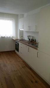 a kitchen with white cabinets and a wooden floor at Appartments Waldblick in Campo Tures