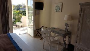 een slaapkamer met een bureau en een bed en een glazen schuifdeur bij Hotel Le Mas Saint Joseph in Saint-Rémy-de-Provence
