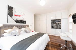 a white bedroom with a large bed and a desk at Whispering Palms in Port Elizabeth