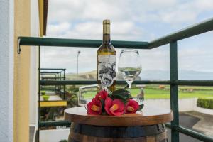 a bottle of wine and a glass and flowers on a barrel at Areal de Santa Bárbara Guest House in Ribeira Grande
