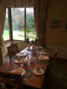 a wooden table with plates and cups on it in front of a window at Caragh Glen B&B in Killorglin