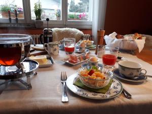 a table with food and drinks and a bowl of fruit at B&B am Park in Rheinfelden