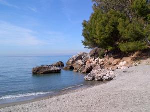 a beach with some rocks in the water at Pension los Verdiales in La Herradura