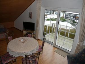 ein Wohnzimmer mit einem Tisch und Stühlen sowie einem Balkon in der Unterkunft Ferienwohnung Gerstmann in Wenholthausen