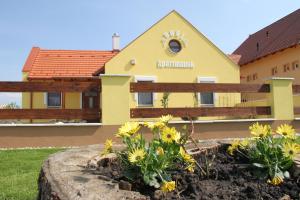 ein gelbes Gebäude mit einem Zaun und Blumen in der Unterkunft BONI APARTMAN Hegykő in Hegykő