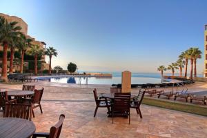 a patio with tables and chairs next to the water at Apartment Samarah Resort D44 at DeadSea, Sea & Pool view-Families & couples only in Sowayma