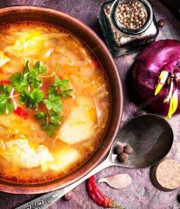 a bowl of soup with vegetables and a spoon at Gdańsk-Apartament Jaglana Spa in Gdańsk