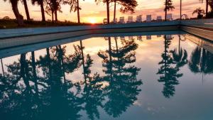 um reflexo de árvores numa piscina ao pôr-do-sol em Hotel Pousada La Vierro em Ponta Grossa