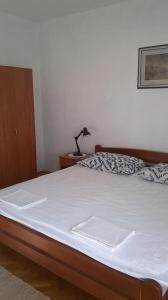 斯塔里格勒的住宿－Apartments Rade，一张带白色床单的床和一张桌子上的台灯