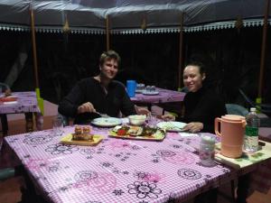 two men sitting at a table with plates of food at Kayaloram Resort in Pūvār