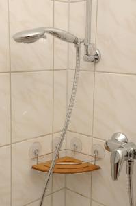 a shower with a shower head and a wooden shelf at Apartments am Brunnen in Quedlinburg +54 photos