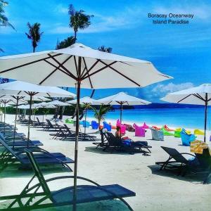 una playa con sillas y sombrillas y el océano en Boracay Oceanway Residences - Island Paradise, en Boracay