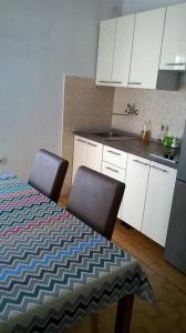 斯塔里格勒的住宿－Apartments Rade，厨房配有白色橱柜和一张桌子及两把椅子