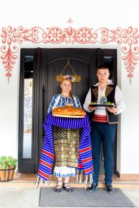 um homem e uma mulher com roupas tradicionais em pé em frente a uma casa em Conacu´ Boierului em Ponoarele