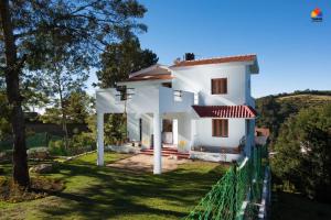 a white house with a fence in front of it at Trippr Kodaikanal Backpacker Hostel in Kodaikānāl