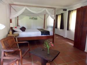 a bedroom with a canopy bed with a table and a chair at Le Logis de Kep in Kep