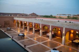 um pátio interior com mesas, cadeiras e água em Côté Sud em Ouarzazate