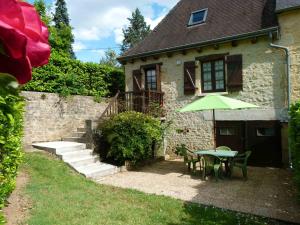 une table avec un parasol vert devant une maison dans l'établissement Petites maisons avec piscine, à Sarlat-la-Canéda