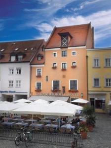 ein Hotel mit Tischen und Sonnenschirmen vor einem Gebäude in der Unterkunft Hotel Gäubodenhof in Straubing