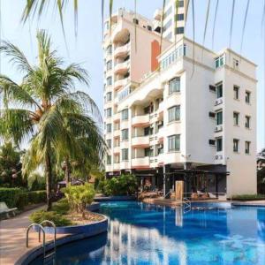 a hotel with a swimming pool in front of a building at Century Bay Private Residences in Bayan Lepas