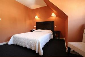 a bedroom with a white bed and orange walls at Hôtel Ariane & SPA in Pontorson