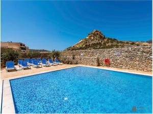 een zwembad met stoelen en een rotswand bij Azure Cottage in Żebbuġ