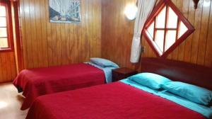 two beds in a room with a window at Hostal ViBeMontt in Puerto Montt +5 photos