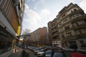 eine Stadtstraße mit parkenden Autos und Gebäuden in der Unterkunft Central Up Studio in Bukarest