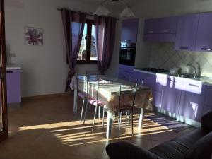 ブドーニにあるcasa vacanza gabriele S1のキッチン(紫色のキャビネット、テーブル、椅子付)