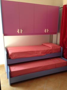 ブドーニにあるcasa vacanza gabriele S1の二段ベッド2組(紫色のキャビネット付)が備わる客室です。