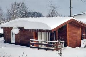 a log cabin with snow on top of it at Camping Fraiteux in Plombières-les-Bains