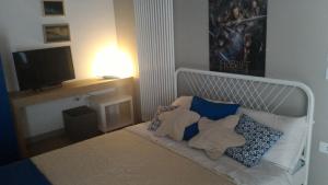 een slaapkamer met een bed met blauwe kussens en een televisie bij Cinquelune Apartment in Rosà