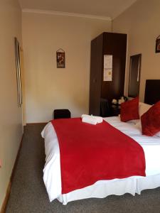 a hotel room with a large bed with a red blanket at Sekelbos Guesthouse in Pretoria