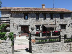 une maison en pierre avec une clôture devant elle dans l'établissement Posada Rural La Flor, à Las Navas del Marqués